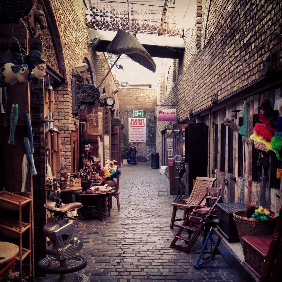 Free Image of A brick alleyway with chairs and other objects 
