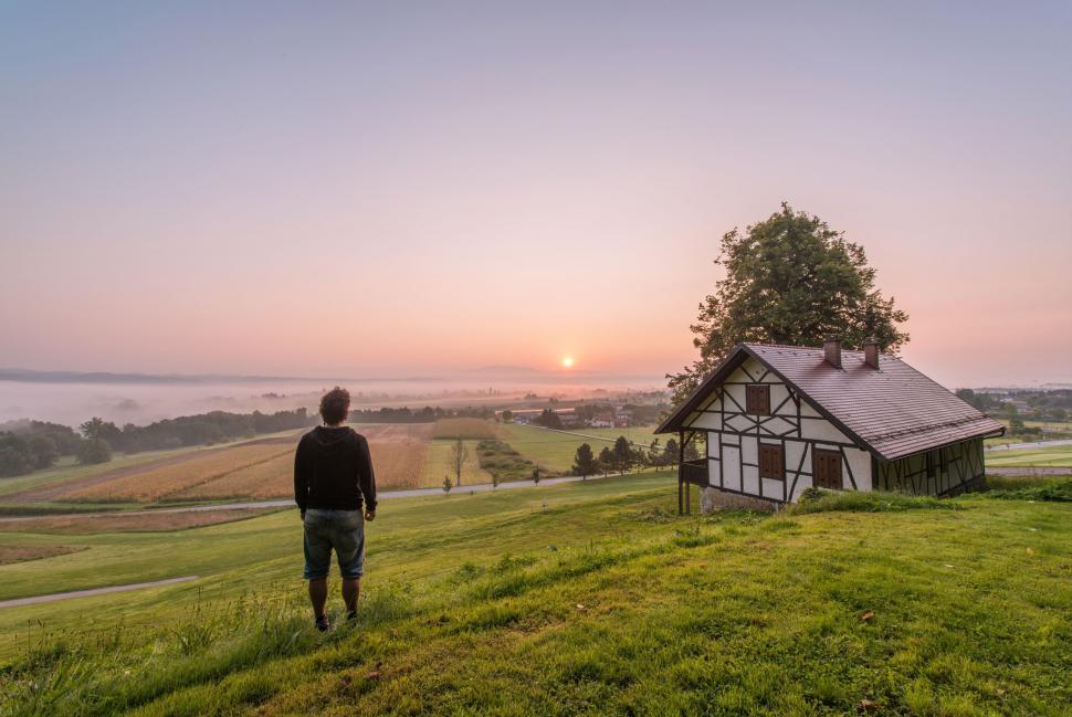 Free Image of A man standing on a hill overlooking a house 