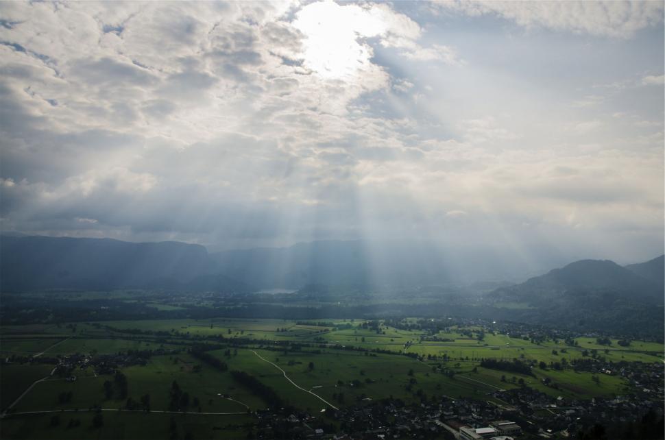 Free Image of Sun shining through the clouds over a valley 
