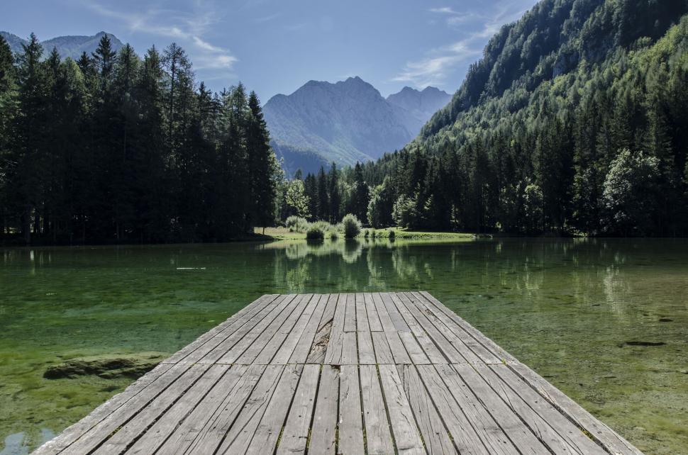 Free Image of A dock on a lake with trees and mountains in the background 