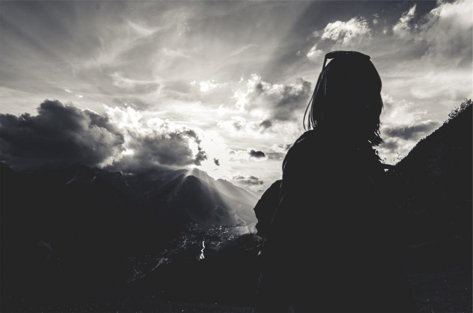 Free Image of A person standing on a mountain looking at the sun 