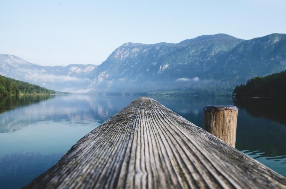 Free Image of A wooden dock with a body of water and mountains in the background 