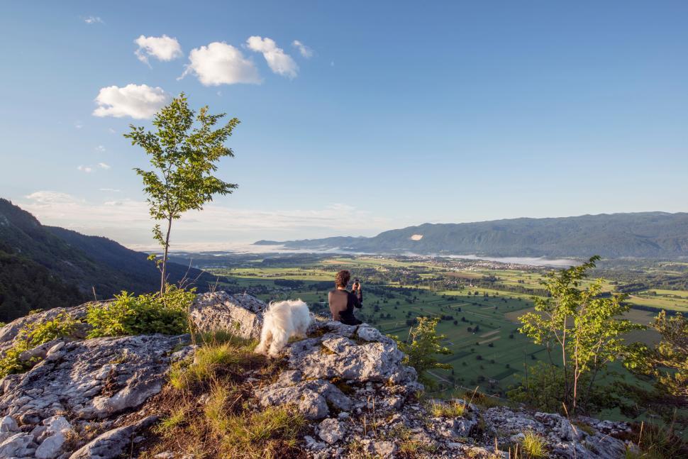 Free Image of A person sitting on a rock looking at a landscape 