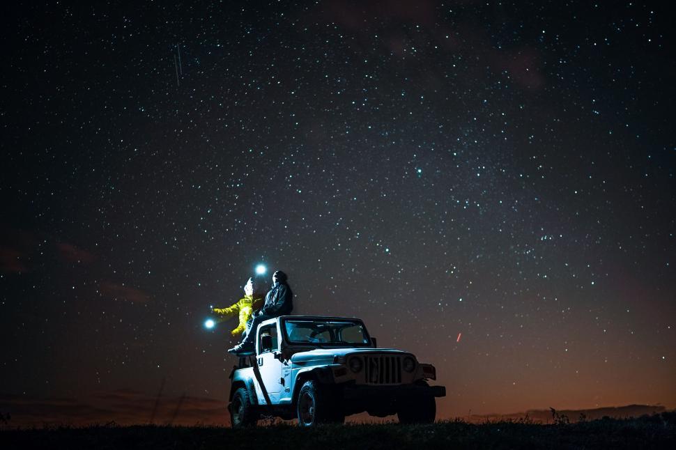 Free Image of A person sitting on top of a car with a flashlight 