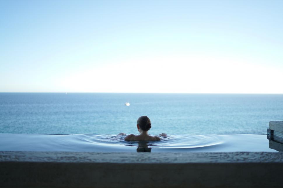 Free Image of A woman in a pool with a body of water in the background 