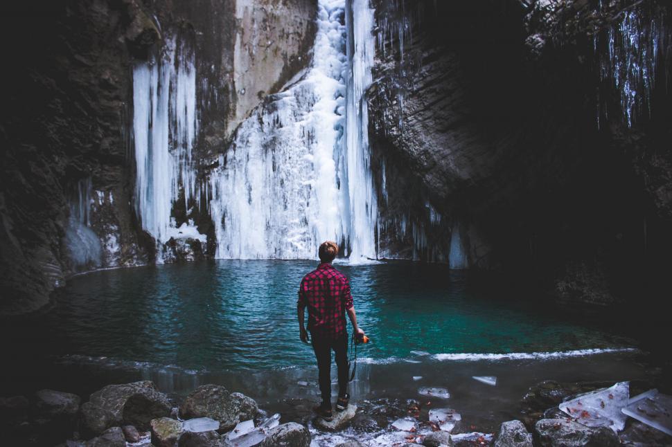 Free Image of A man standing in front of a waterfall 