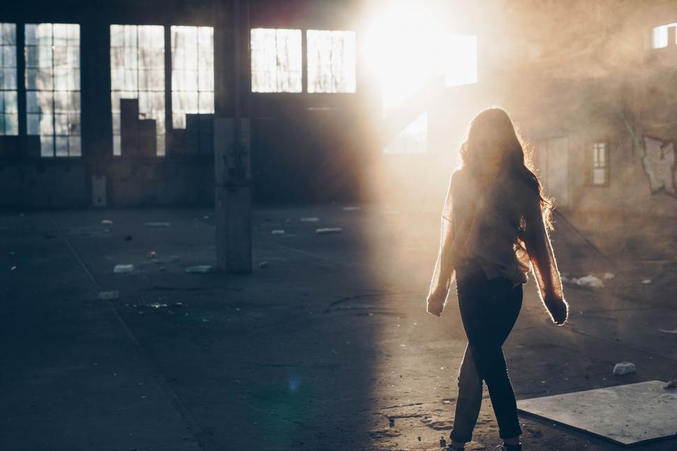 Free Image of A woman standing in a building with sunlight 