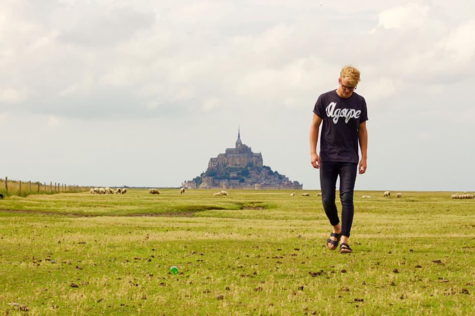 Free Image of A man walking in a field with a castle in the background 