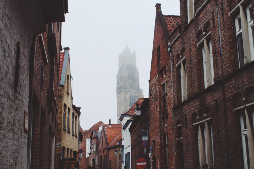 Free Image of A street with brick buildings and a tower in the background 