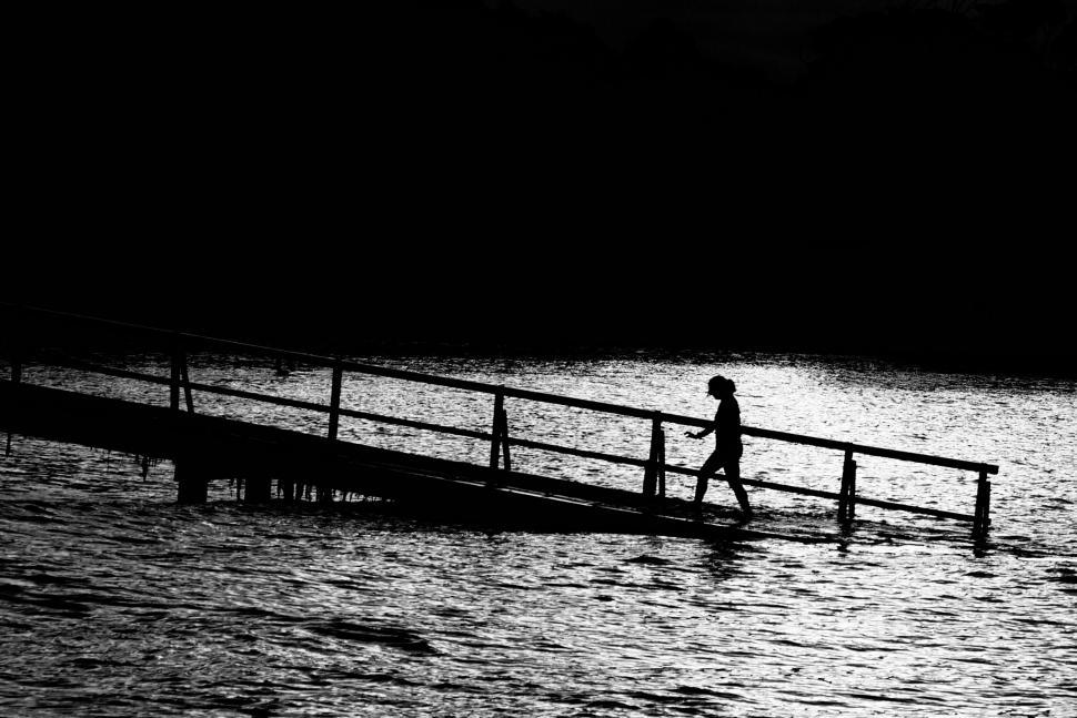 Free Image of A person walking on a bridge over water 
