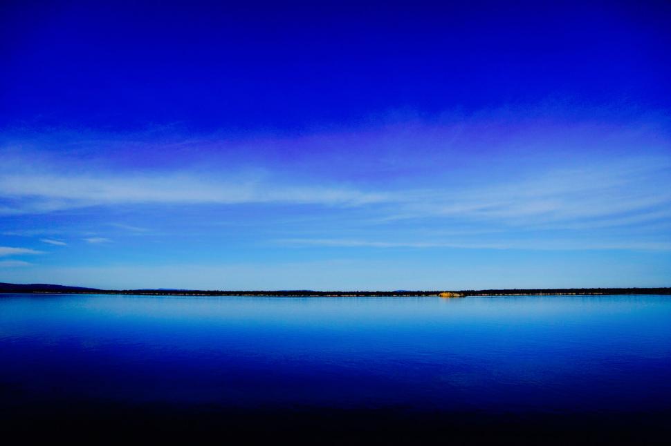 Free Image of A body of water with a blue sky and clouds 