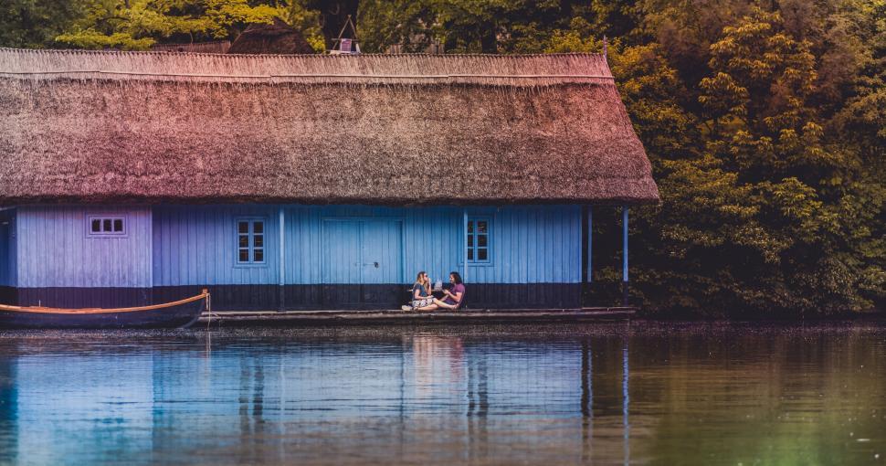 Free Image of Two people sitting on a dock by a lake 