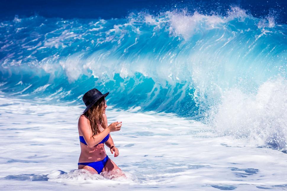 Free Image of A woman in a garment sitting on a surfboard in the ocean 
