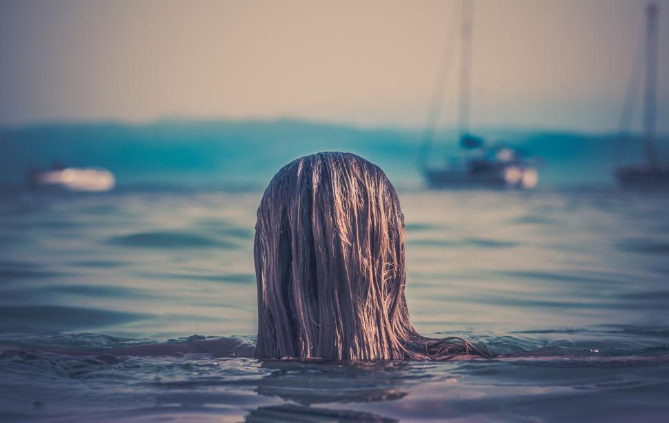Free Image of A person s head in the water with a boat in the background 