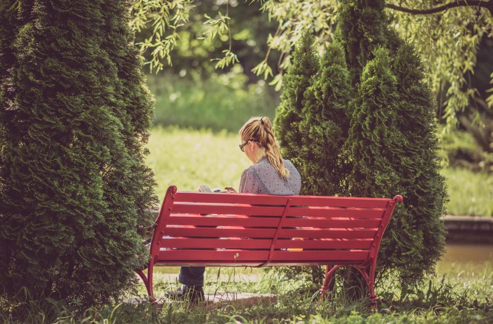 Free Image of A woman sitting on a red bench 