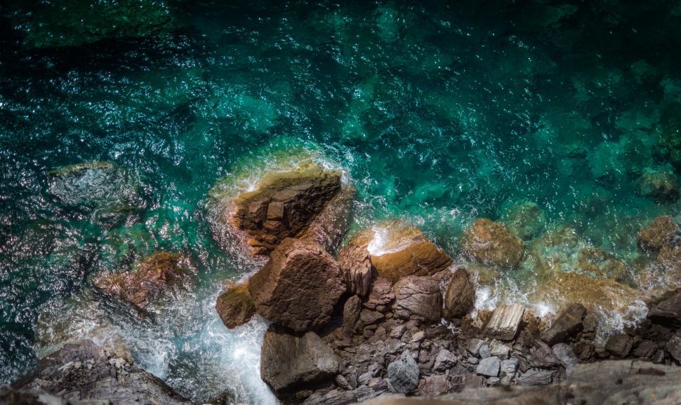 Free Image of A rocky shore with blue water 