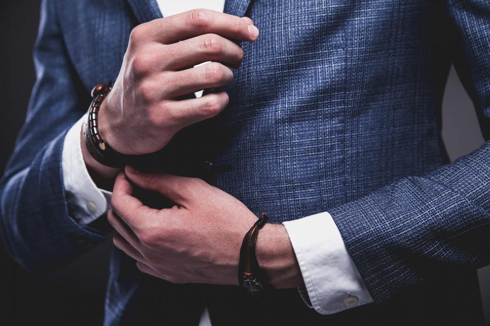 Free Image of A close up of a man s hands buttoning a jacket 