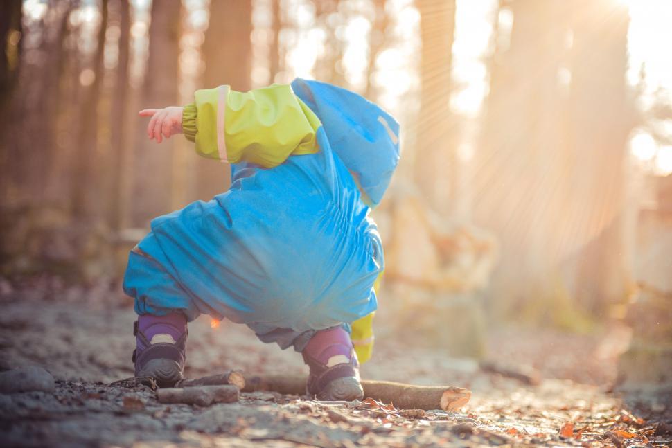 Free Image of A child in a blue jacket and boots playing in the woods 