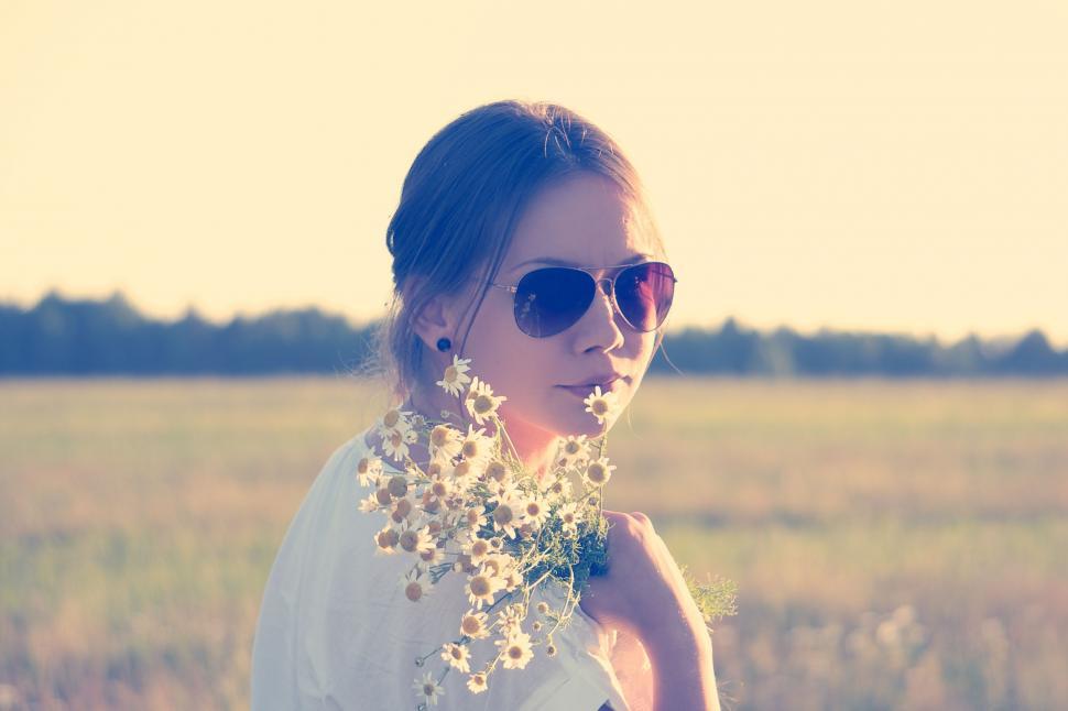 Free Image of A woman wearing sunglasses holding a bouquet of flowers 