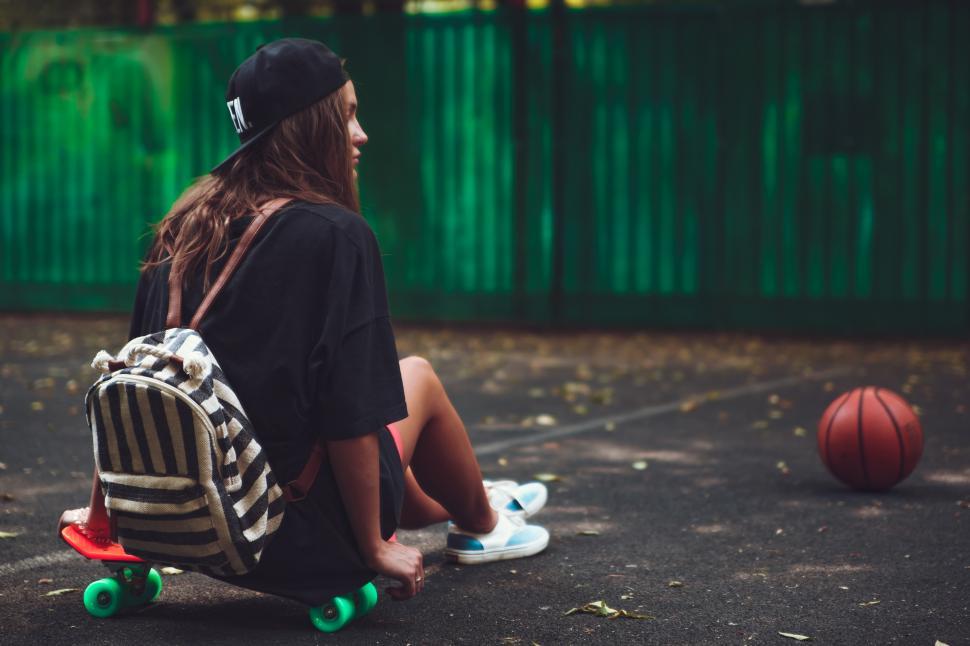 Free Image of A woman sitting on a skateboard 