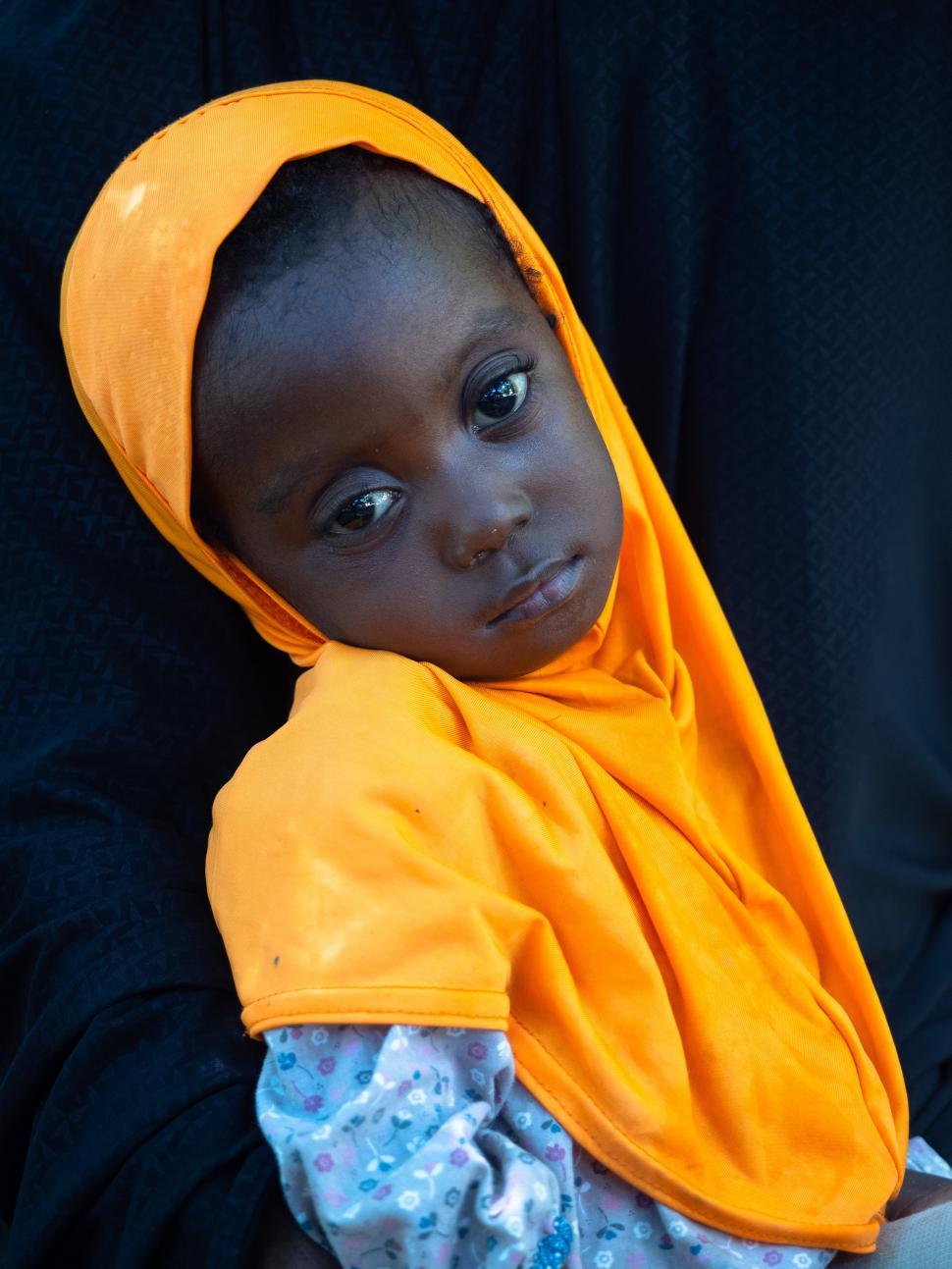 Free Image of A child wearing an orange head scarf 