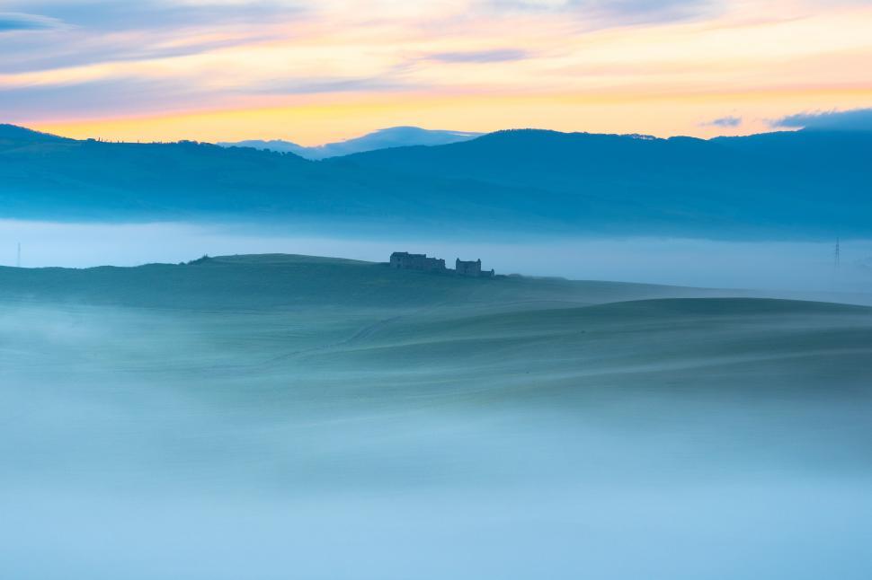 Free Image of A foggy landscape with a house on top of it 