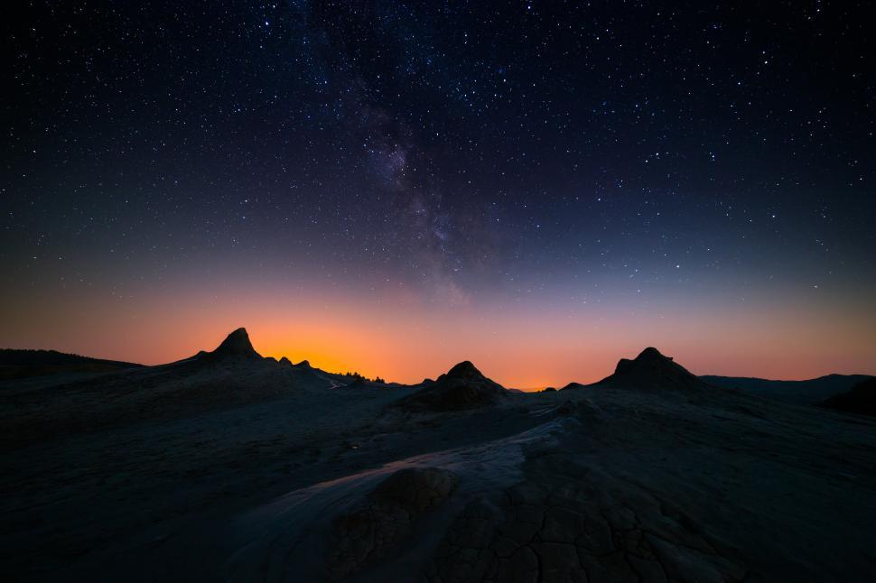 Free Image of A landscape of a desert with a sunset and stars in the sky 