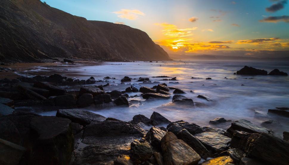 Free Image of A rocky beach with a sunset 