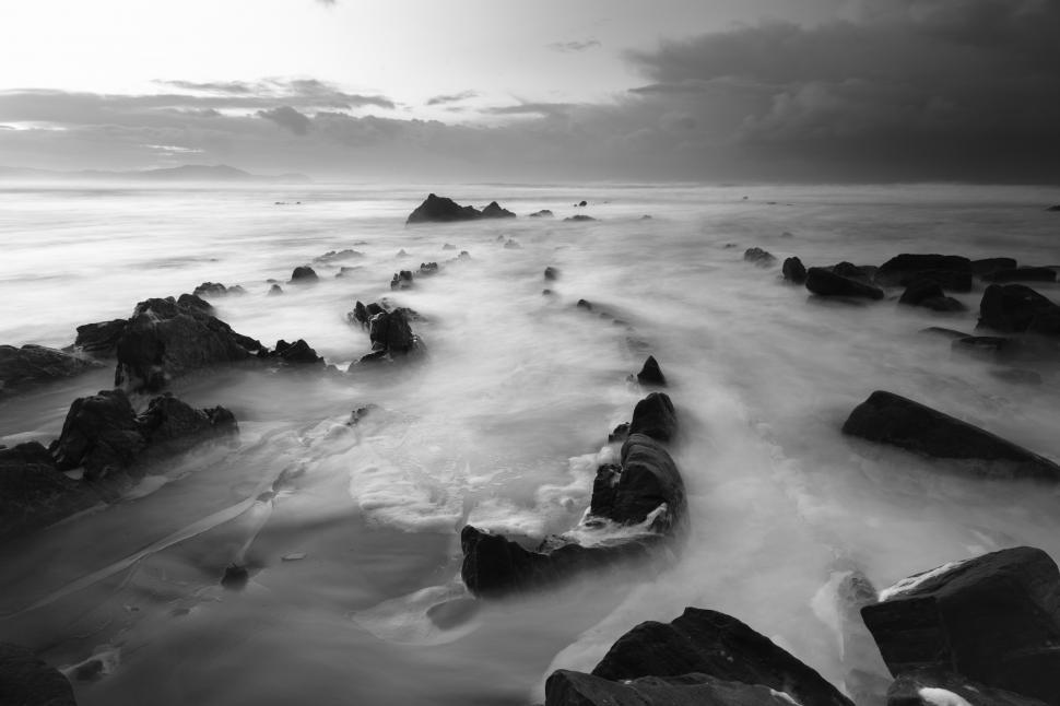 Free Image of A rocky beach with waves crashing on rocks 