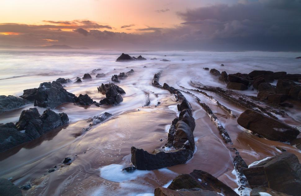 Free Image of Rocks on a beach with waves crashing on rocks 