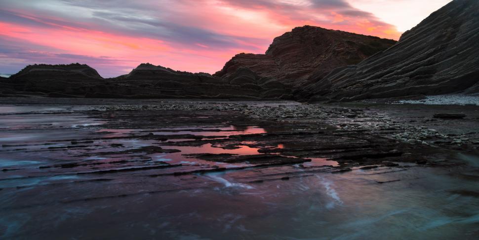 Free Image of A rocky beach with a pink sky 