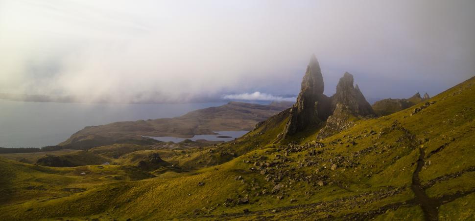 Free Image of A rocky hills with water in the background with the storr in the background 