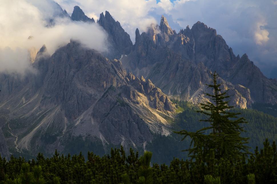 Free Image of A mountain range with clouds and trees 