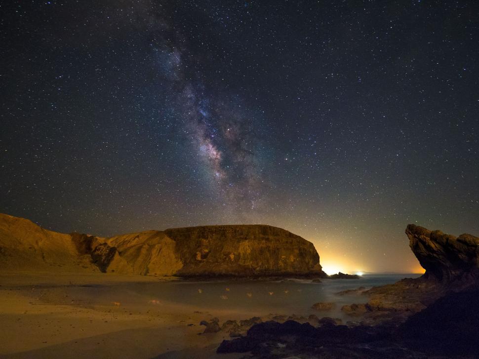 Free Image of A rocky beach at night with stars in the sky 