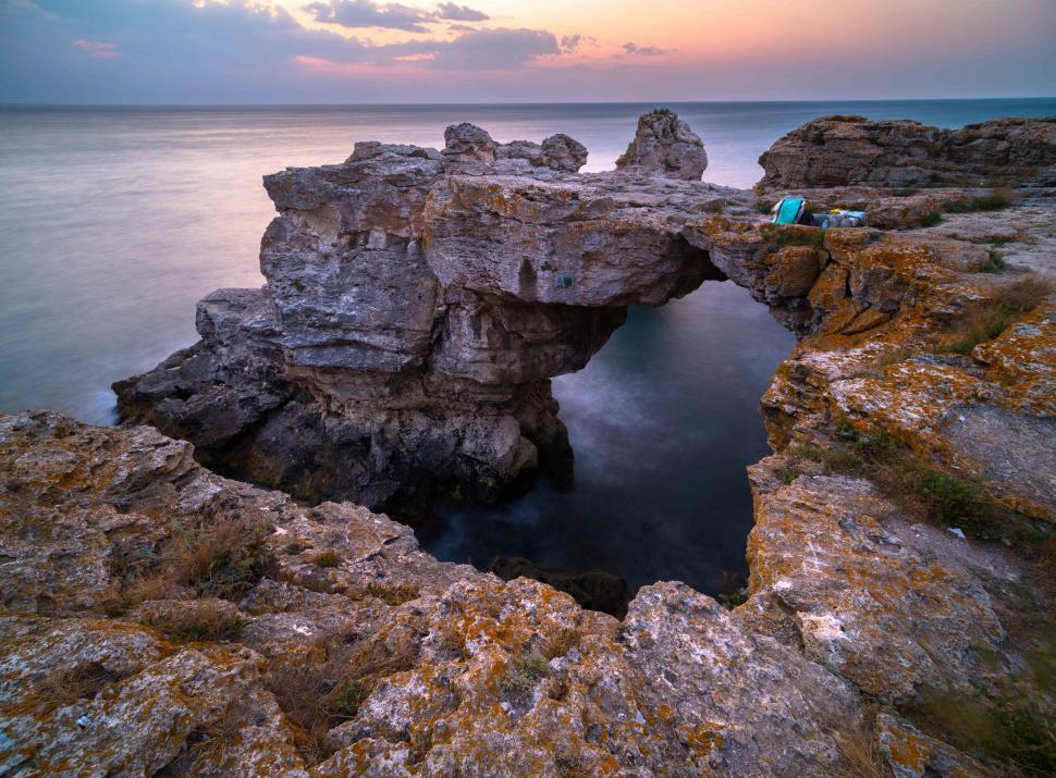 Free Image of A rock formation with a bridge over water 