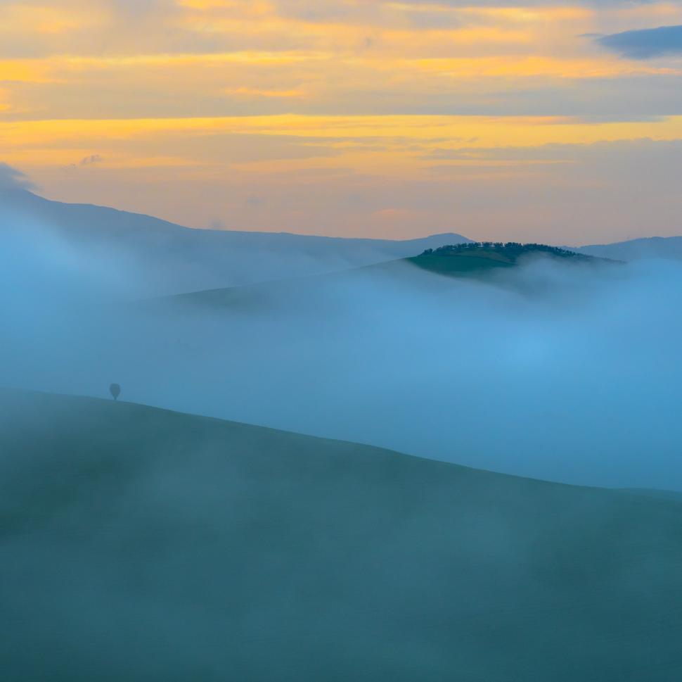 Free Image of A foggy landscape with hills and trees 