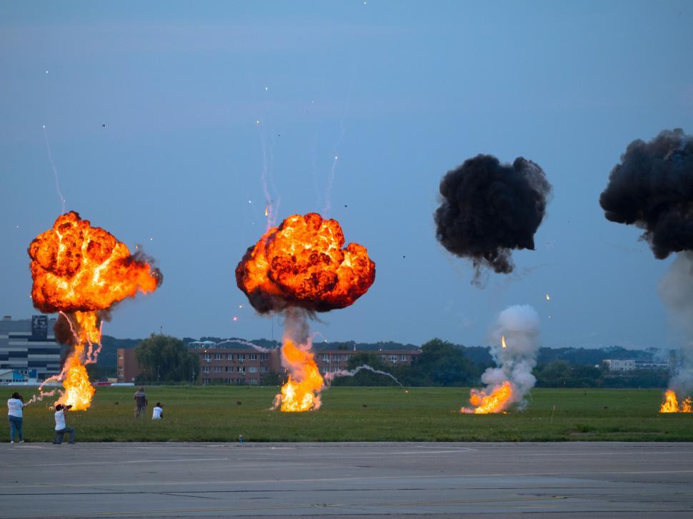 Free Image of A group of people standing in a field with a group of explosions 