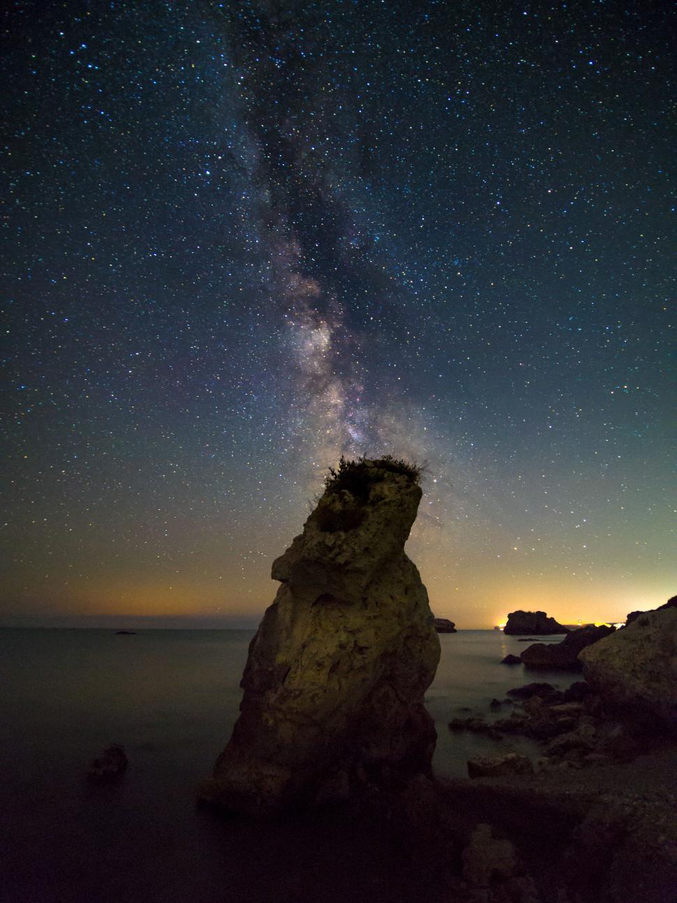 Free Image of A rock formation in the water at night 