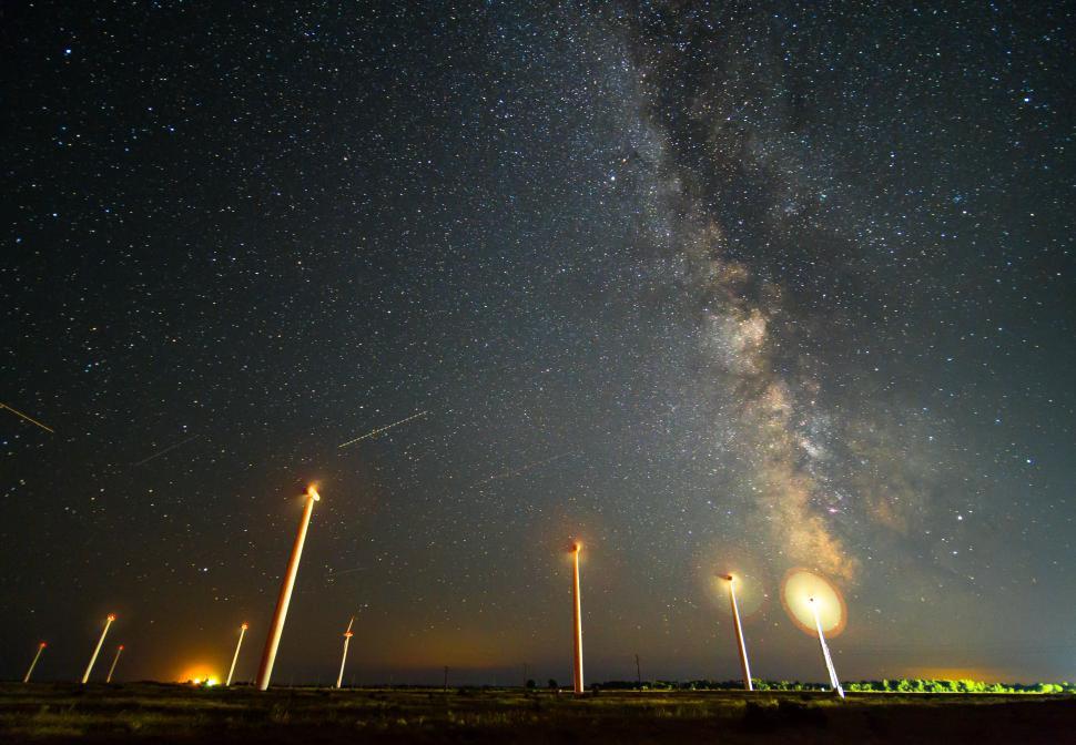Free Image of A group of wind turbines in a field at night 