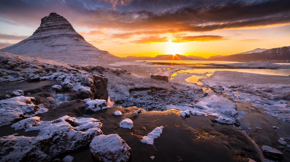 Free Image of A snowy landscape with a mountain and a sunset 