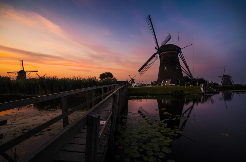 Free Image of A windmill next to a body of water 