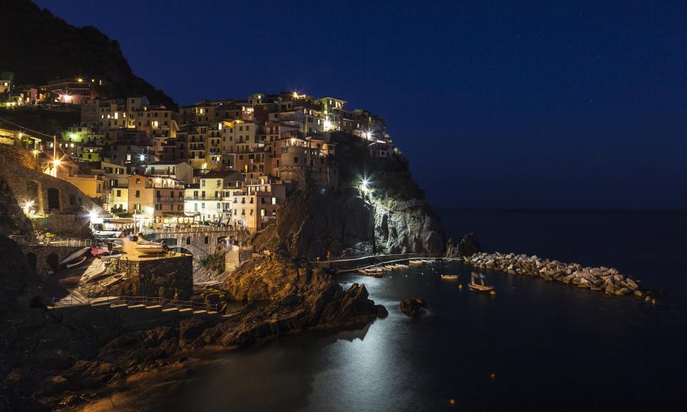 Free Image of A lit up buildings on a cliff above water 