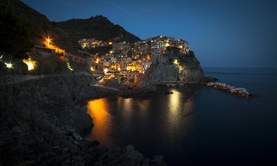 Free Image of A lit up buildings on a hill above a body of water 