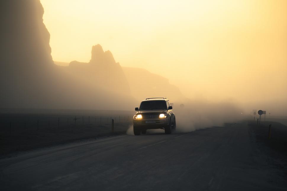 Free Image of A car driving on a road with fog 