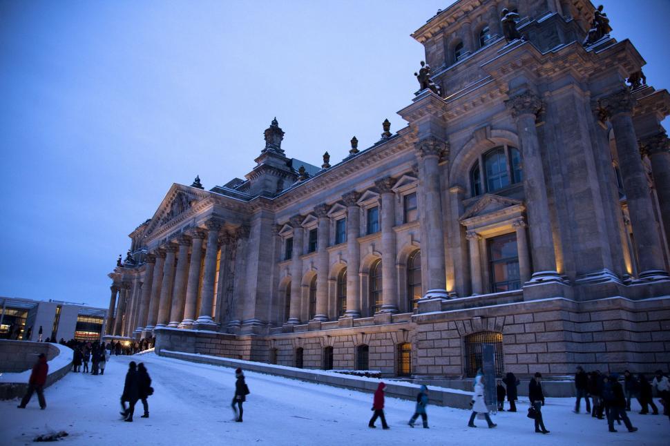Free Image of Reichtstag Building, Berlin, Germany with columns and people walking in the snow 