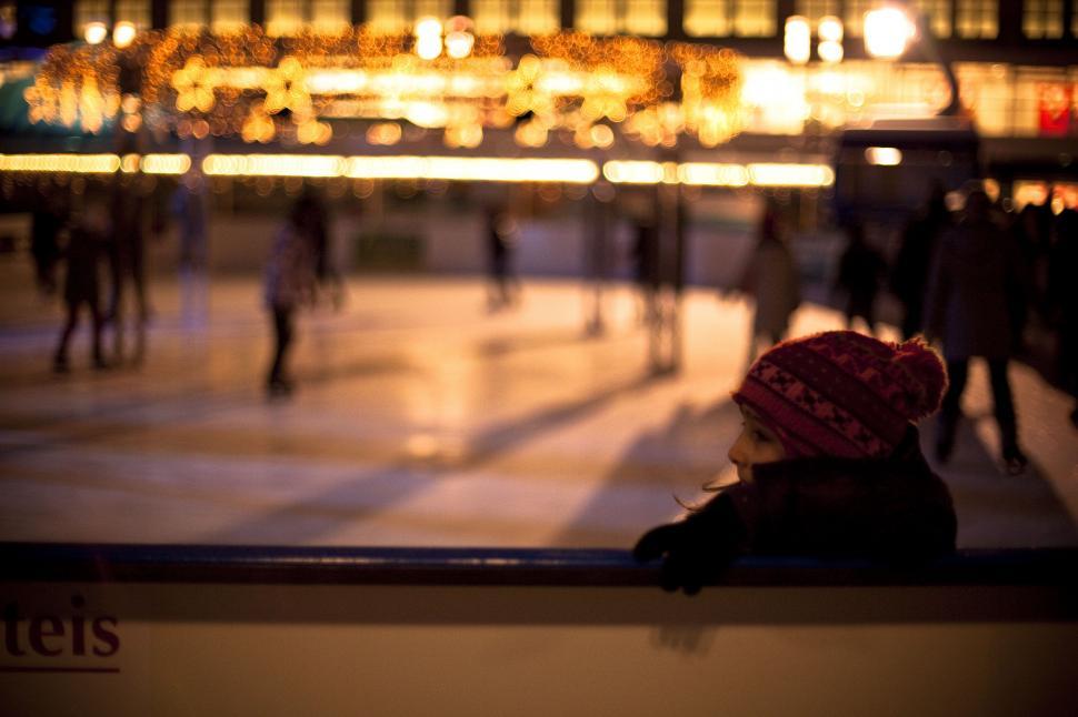 Free Image of A girl looking out a window at an ice rink 