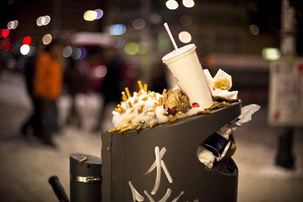 Free Image of A trash can with cigarette butts and a drink cup on top 