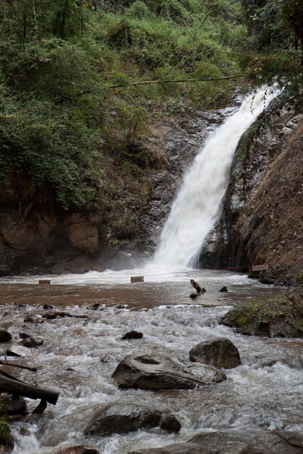 Free Image of Man Standing in River Next to Waterfall 