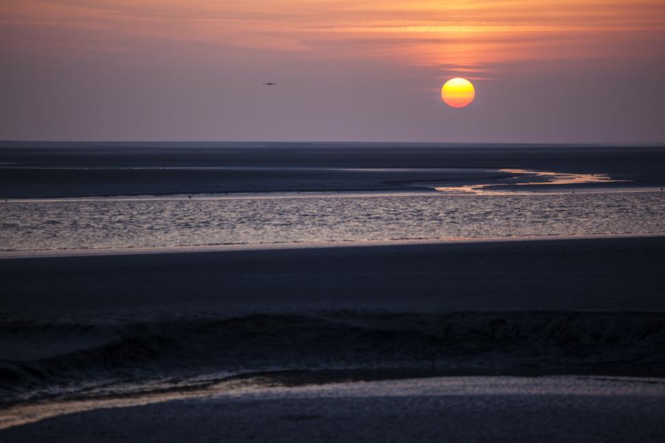 Free Image of A sunset over a beach 
