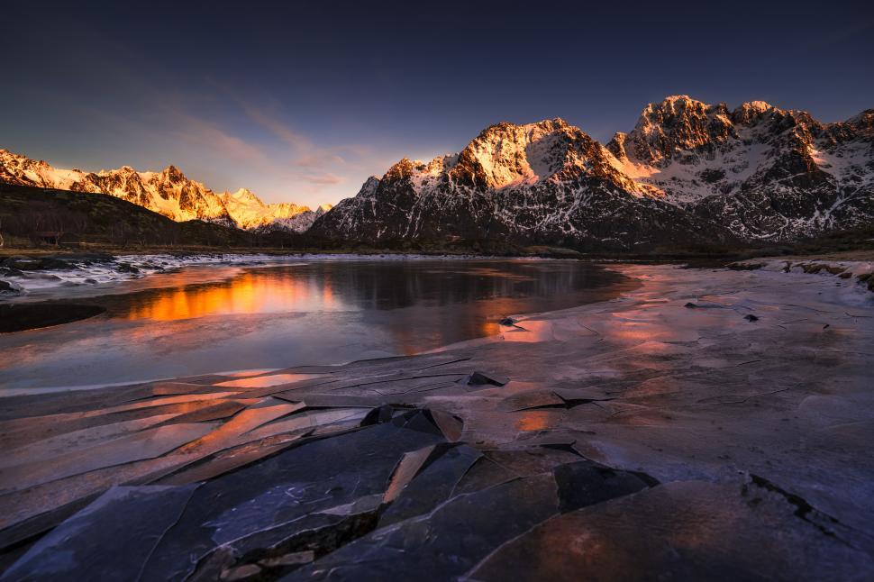 Free Image of A frozen lake with snow covered mountains in the background 